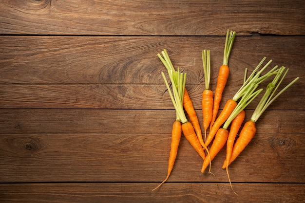 Zanahorias frescas en tabla de cortar de madera y fondo de madera