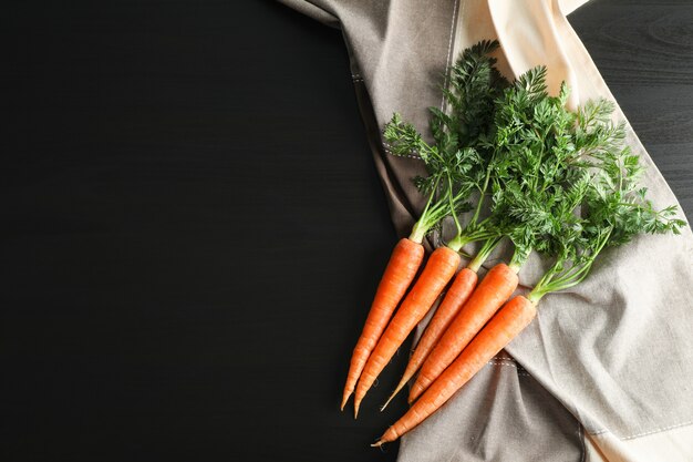 Zanahorias maduras en mesa negra, espacio para texto