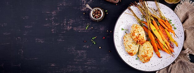 Zanahorias orgánicas al horno con tomillo y chuleta / albóndigas de carne de pollo y calabacín. Comida dietetica. Bandera.