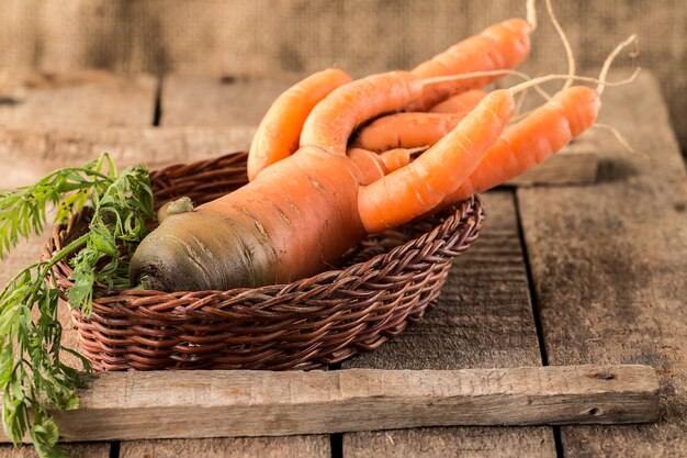 Zanahorias orgánicas frescas en una canasta sobre superficie de madera