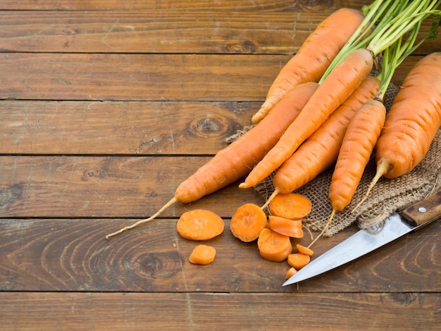 Zanahorias orgánicas frescas con hojas verdes sobre fondo de madera Verduras