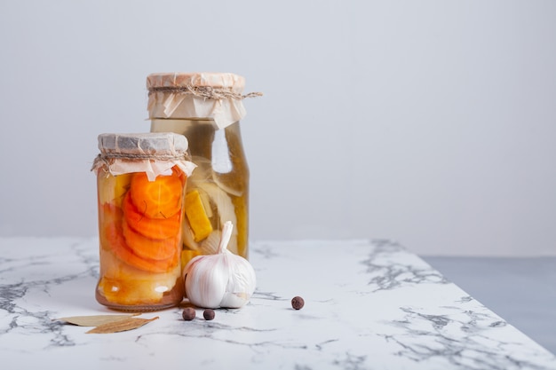 Zanahorias y pepinos fermentados en un frasco de vidrio sobre la mesa