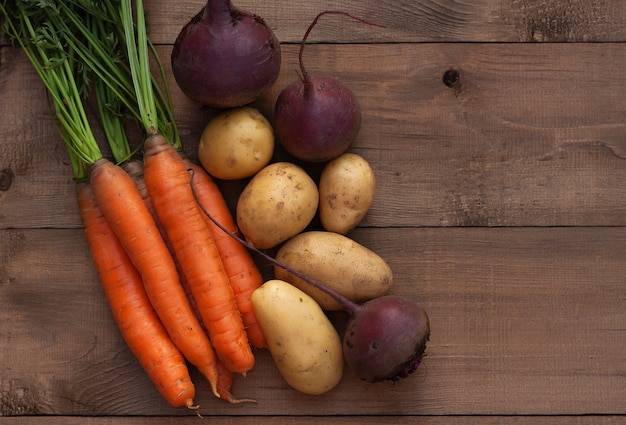 Zanahorias, remolachas y patatas sobre una superficie de madera