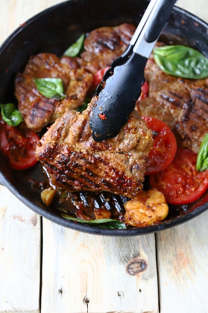 Zange für Fleisch und eine Bratpfanne mit Steaks