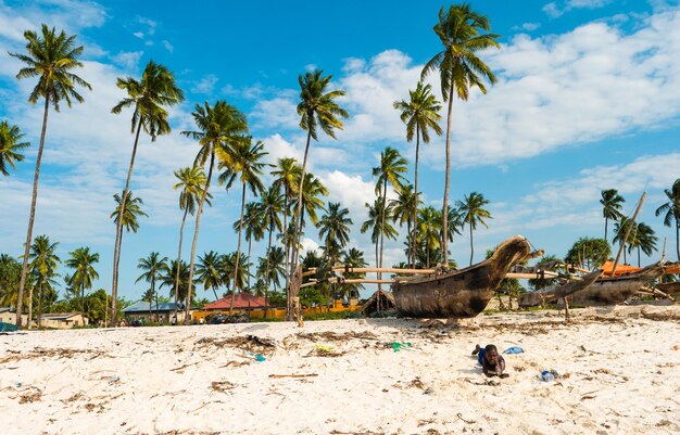 Zanzíbar Tanzania julio 09 2016 Niño local en Zanzíbar Tanzania tendido en una playa de arena enorme barco rústico sentado en la orilla