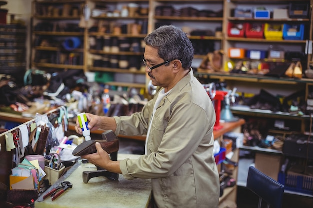 Foto zapatero aplicando pegamento en el zapato