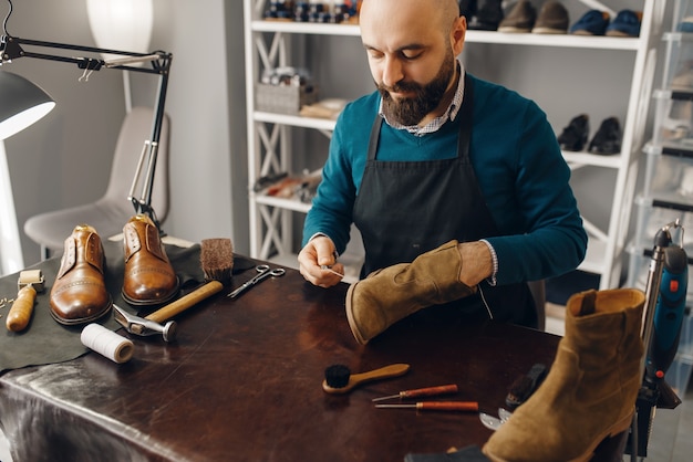 Foto zapatero cose el zapato, servicio de reparación de calzado