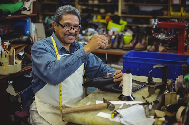 Foto zapatero cosiendo suela de zapato con aguja