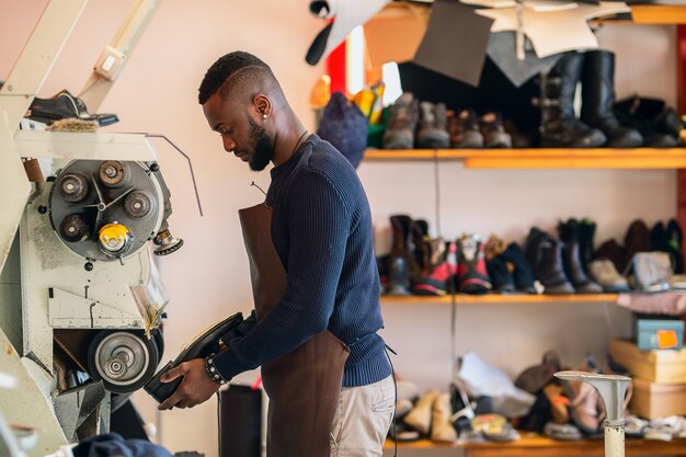 Zapatero realiza zapatos en la máquina amoladora artesanal de estudio.