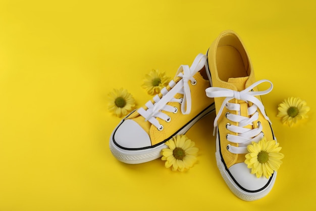 Zapatillas amarillas con flores sobre fondo amarillo