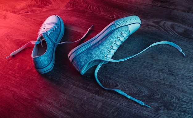 Zapatillas antiguas en un piso de madera con un resplandor degradado de neón rojo-azul