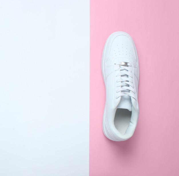 Zapatillas blancas de moda en una mesa de colores pastel, minimalismo, vista superior, diseño creativo