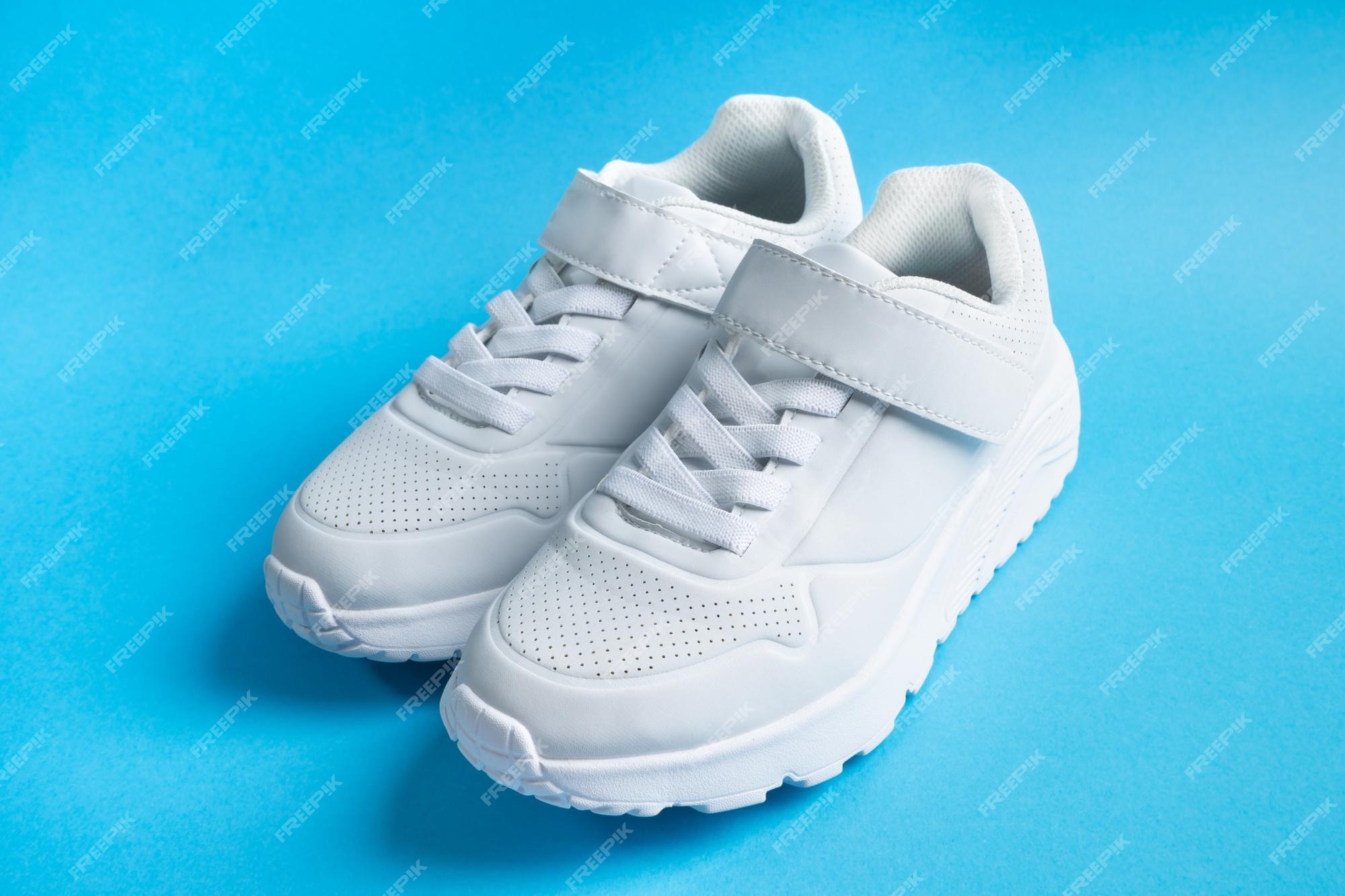 Zapatillas blancas para niños con velcro sobre fondo azul Foto Premium