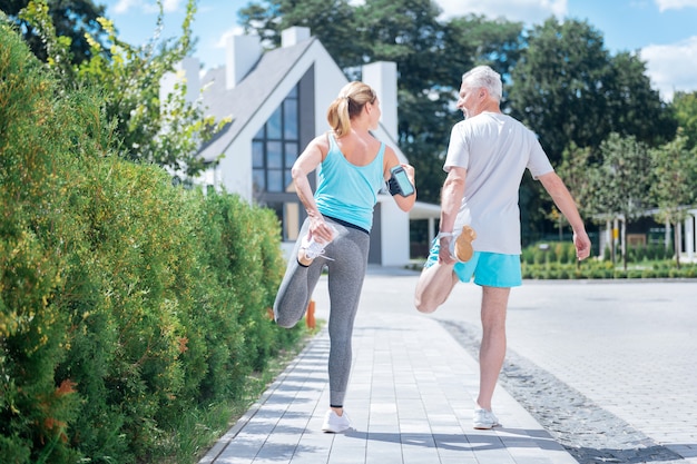 Zapatillas blancas. Pareja madura vistiendo cómodas zapatillas blancas haciendo deporte juntos disfrutando de una agradable y cálida mañana de verano