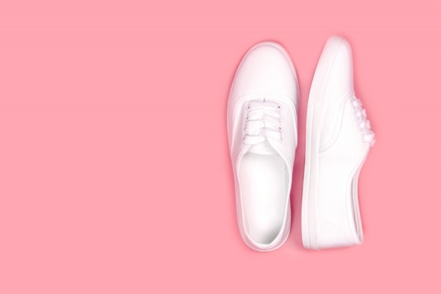 Foto zapatillas blancas sobre fondo rosa