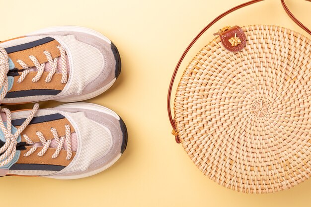 Zapatillas y bolso de ratán sobre fondo amarillo. Concepto de viaje. Lay Flat - Imagen