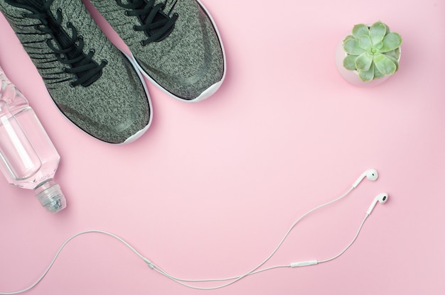 Zapatillas con una botella de agua y auriculares blancos.