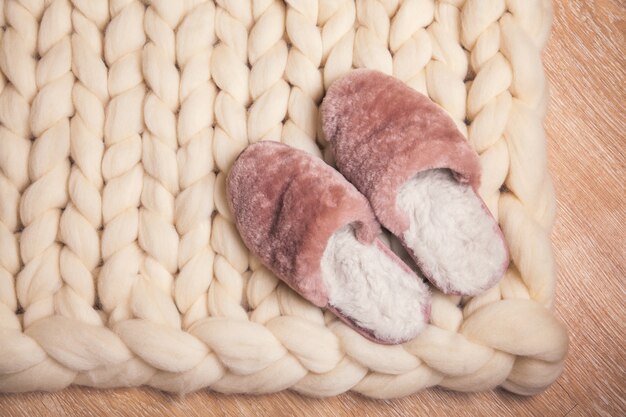 Zapatillas de casa confeccionadas en piel sobre fondo de tartán de lana merino blanca. El ambiente hogareño y confortable. Espacio de copia plano.