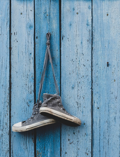 Zapatillas de deporte muy viejas colgando de un clavo.