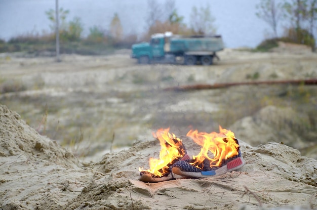 zapatillas de deporte o zapatillas de gimnasia en llamas en la costa de la playa de arena atleta quemado esfuerzo físico durante el concepto de entrenamiento