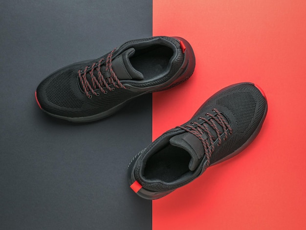 Zapatillas deportivas negras con cordones rojos sobre fondo negro y rojo Concepto deportivo minimalista