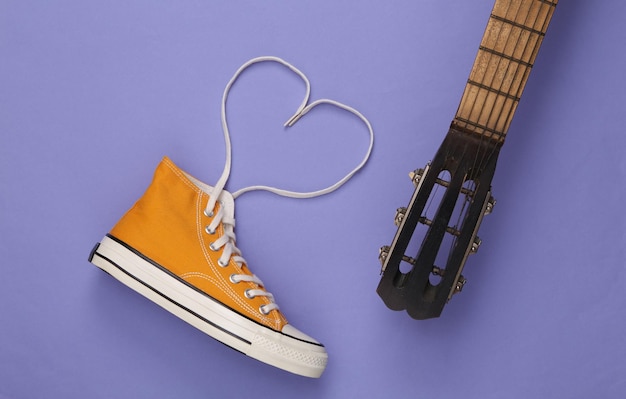 Zapatillas de diseño creativo con cordones doblados en forma de corazón y guitarra sobre fondo morado Vista superior