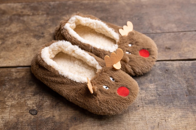 Zapatillas divertidas en forma de un ciervo en un viejo fondo de madera imagen de Navidad Copiar espacio