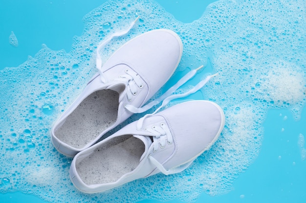 Zapatillas con espuma de detergente en polvo de disolución en agua. Lavado de zapatos sucios.