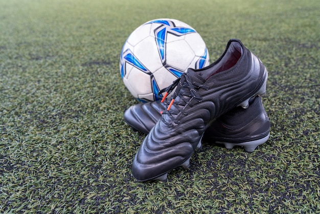 Foto zapatillas de fútbol con balón de fútbol en campo de césped artificial