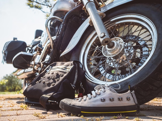 Foto zapatillas grises con calaveras y cordones plateados y una mochila negra cerca de la rueda de