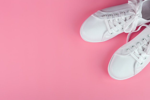 Zapatillas mujer blancas sobre fondo rosa con espacio de copia. vista superior, endecha plana.