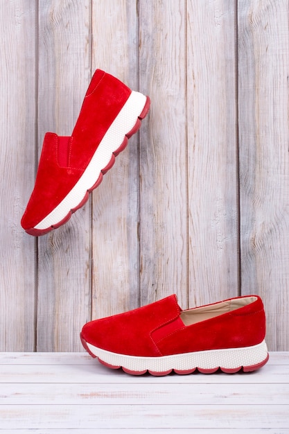 Zapatillas de mujer rojas cuelgan de tablas de madera