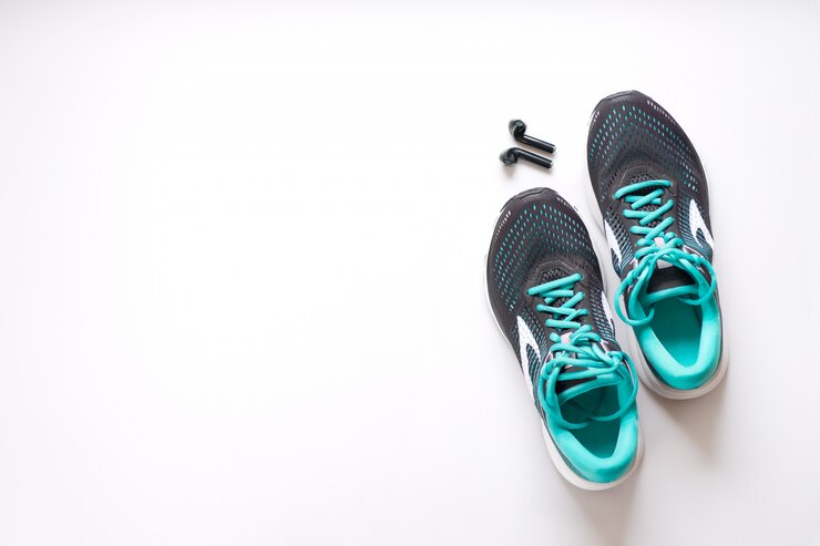 Zapatillas negras para correr con elementos verdes y cordones verdes y auriculares negros.