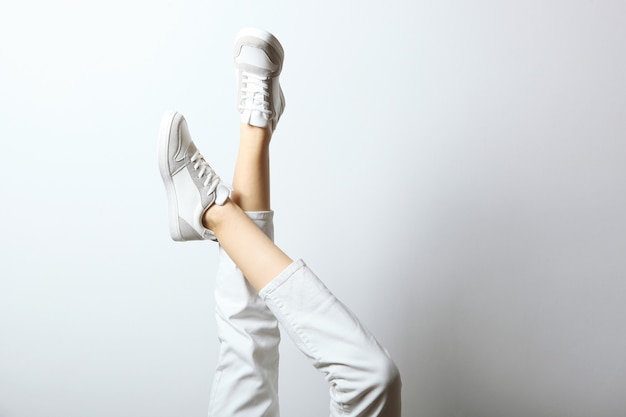 Zapatillas en piernas femeninas sobre un fondo de color