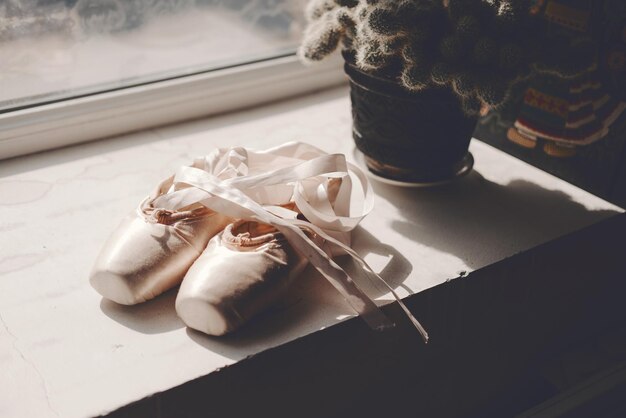 Foto zapatillas de punta de ballet con cinta de seda rosa cerca de la ventana zapatillas de punta viejas con cinta de satén