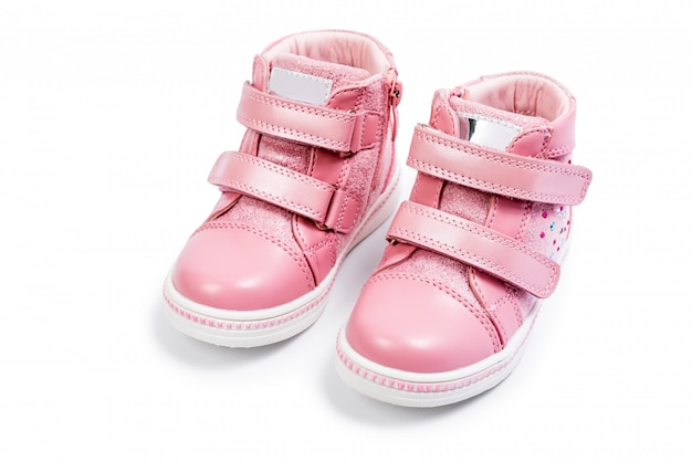 Las zapatillas rosa para niños aisladas sobre un blanco.