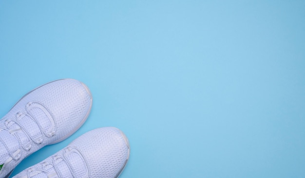 Zapatillas textiles blancas en una vista superior de fondo azul