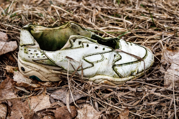 Zapatillas viejas rotas en la hierba sucia.