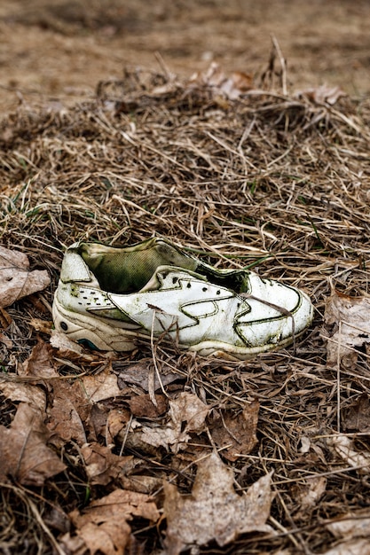 Foto zapatillas viejas rotas en la hierba sucia.