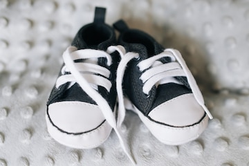 Zapatitos de bebé. zapatillas tejidas a mano para recién nacido niño o niña  en la pared gris.