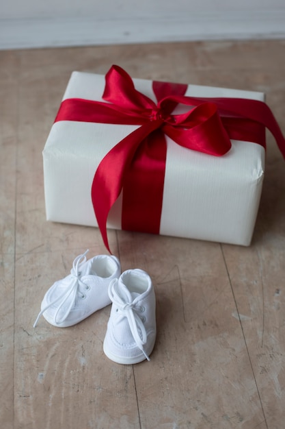 Zapatitos blancos, caja de regalo, sesión de maternidad. Concepto de embarazo feliz