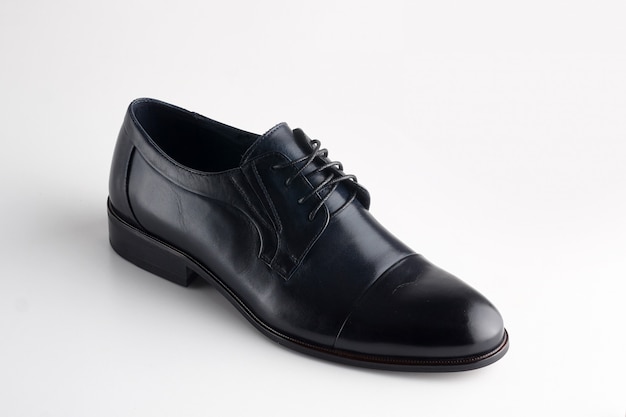 Zapato de cuero negro para hombre con cordones sobre fondo blanco.