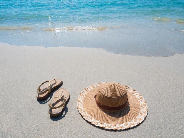 Zapato de mujer y sombrero en la playa con concepto de viajero de olas oceánicas