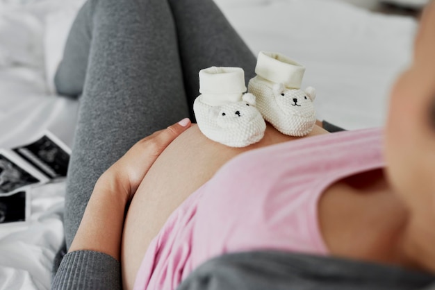 Zapatos de bebé en el abdomen de embarazada.