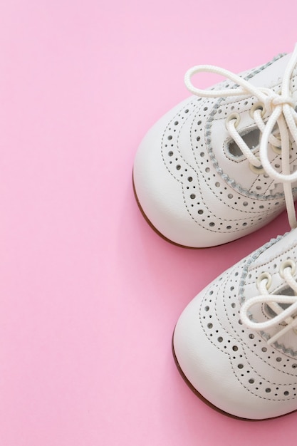 Zapatos de bebé blancos sobre fondo rosa