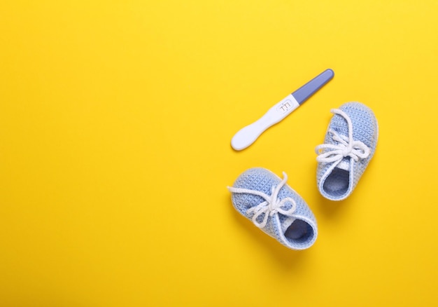 Foto zapatos de bebé de punto azul sobre fondo amarillo vista superior espacio de copia plana