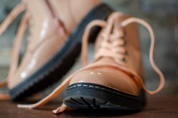 Zapatos beige para niños con el telón de fondo de un muro de piedra