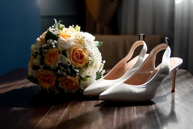 Zapatos blancos de la novia en un estante marrón con un ramo de flores ideas para agencias de bodas