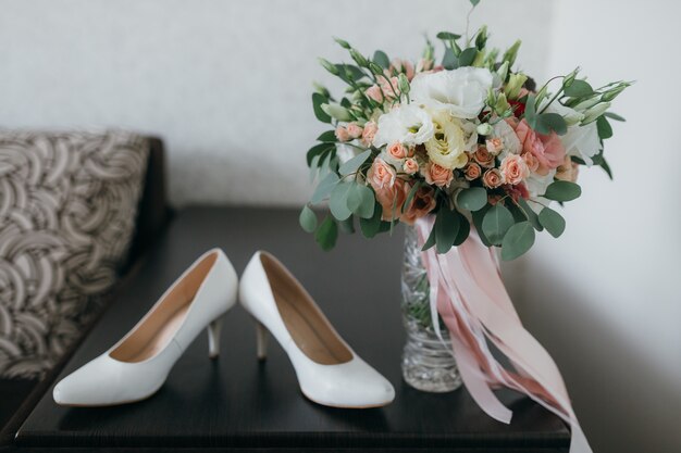 Zapatos blancos y un ramo nupcial para la boda.