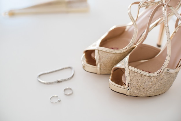 Zapatos de boda nupciales y joyas de acento, pendientes y pulsera.